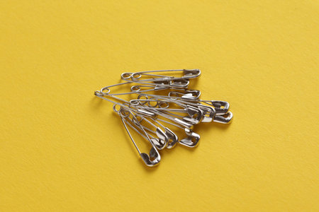 Metal pins on yellow background close up