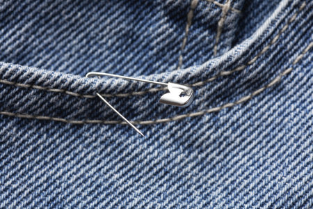 Metal pin on blue jeans