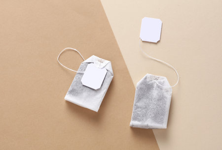 Tea bags with white labels on strings, beige background. Mockup for design, brandingの写真素材