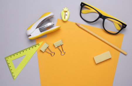 Yellow sheets of paper with eyeglasses and stationery on gray backgroundの写真素材