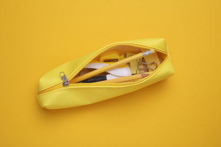 Yellow pencil case with stationery on yellow background. Flat layの写真素材