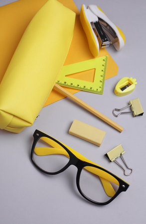 Yellow pencil case with stationery on grey background. Flat layの写真素材