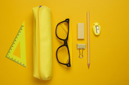 Yellow pencil case with stationery on yellow background. Flat layの写真素材