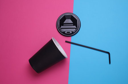 Black disposable cup for hot drinks with straw and lid on pink blue backgroundの写真素材