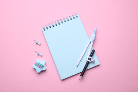 Blue notebook with stationery on pink background. Top viewの写真素材