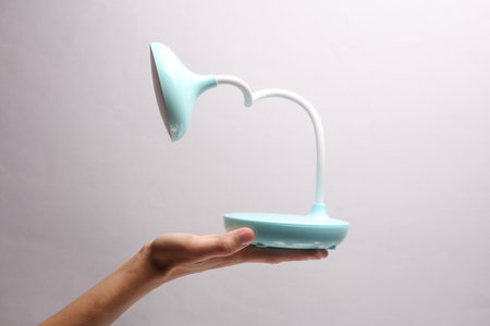 Female hand holding wireless led lamp on gray backgroundの写真素材