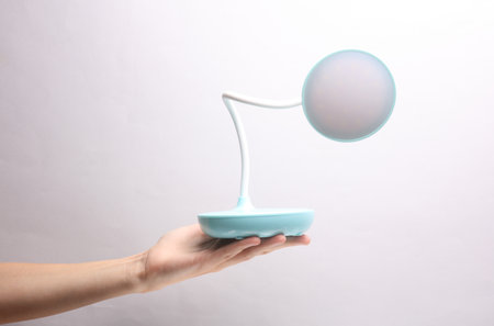 Female hand holding wireless led lamp on grey backgroundの写真素材