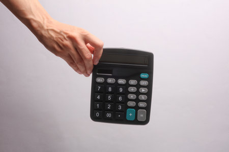 Female hand holding calculator on gray backgroundの写真素材