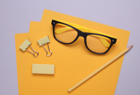 Yellow sheets of paper with eyeglasses and stationery on gray backgroundの写真素材