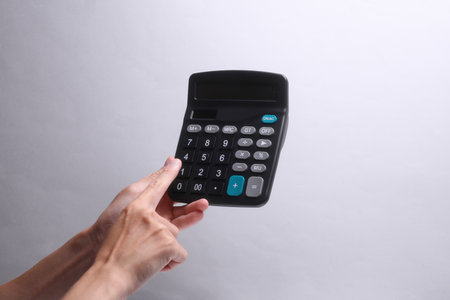 Female hand holding calculator on gray backgroundの写真素材