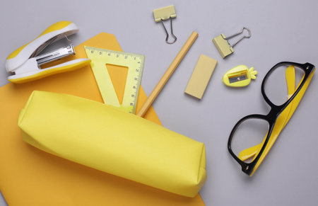 Yellow pencil case with stationery on gray background. Flat layの写真素材