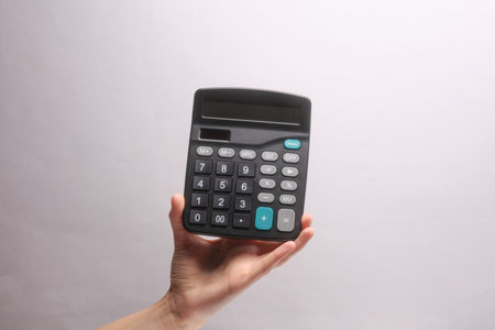 Female hand holding calculator on gray backgroundの写真素材