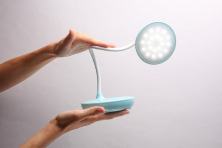Female hand holding wireless led lamp on gray backgroundの写真素材