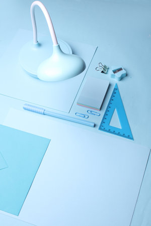 Blue Stationery set on light blue background. Back to school, education, office supplies. Monochrome photo. Flat lay. Top view. Creative layoutの写真素材