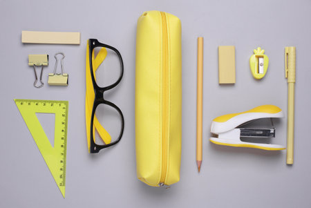 Yellow pencil case with stationery on grey background. Flat layの写真素材
