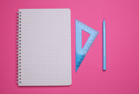 Notebook with triangle ruler and pen on pink backgroundの写真素材