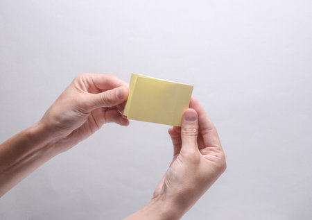 Female hands holding memo paper sticker on gray backgroundの写真素材
