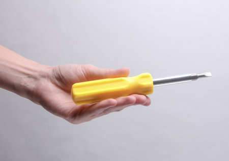 Female hand holding screwdriver on gray backgroundの写真素材