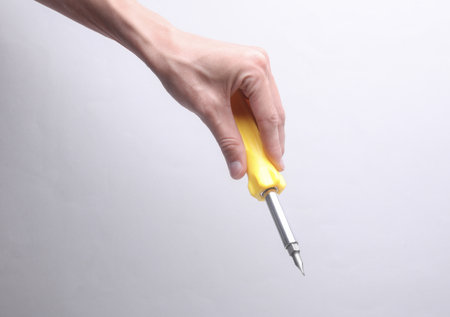 Female hand holding screwdriver on gray backgroundの写真素材