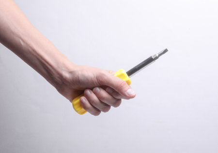 Female hand holding screwdriver on gray backgroundの写真素材