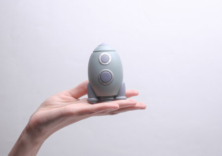 Female hand holding a toy space shuttle model on a gray background. Startupの写真素材