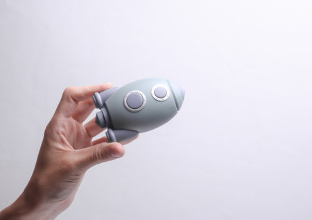 Female hand holding a toy space shuttle model on a gray background. Startupの写真素材