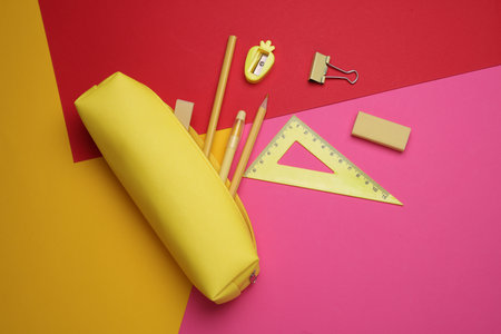 Yellow pencil case with stationery on colored background. Flat layの写真素材