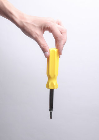 Female hand holding screwdriver on gray backgroundの写真素材