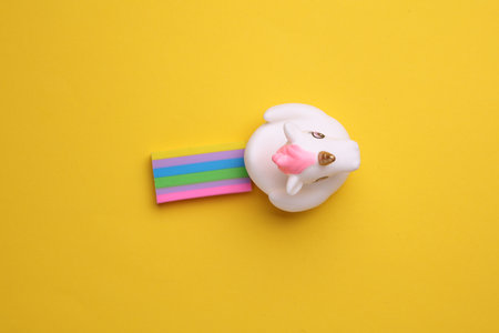 Rubber unicorn with rainbow on yellow background. Creative ideaの写真素材