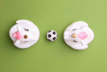 Rubber bath unicorns with soccer ball on green background. Top view. Sports conceptの写真素材