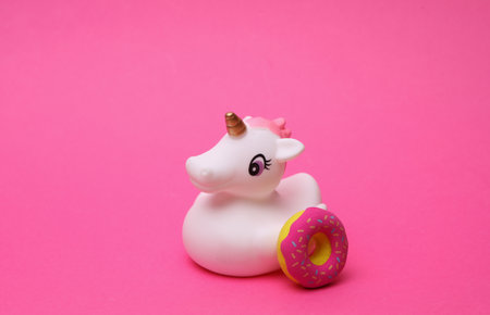 Rubber bath unicorn with donut on pink background.の写真素材