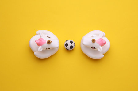 Rubber bath unicorns with soccer ball on a yellow background. Top view. Sports conceptの写真素材