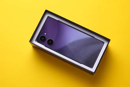 New modern smartphone in a box on yellow backgroundの写真素材
