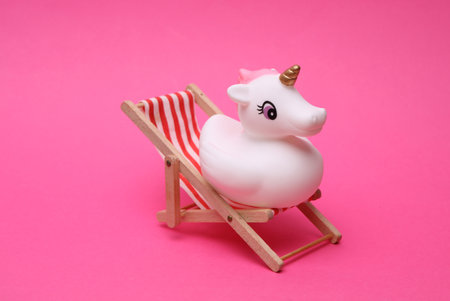 Rubber bath unicorn with deck chair on pink background. Vocationの写真素材