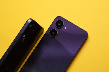 Two modern smartphones with dual camera, view from the back cover. Yellow backgroundの写真素材