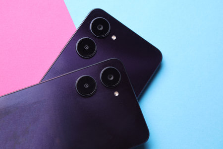 Two modern smartphones with dual camera, view from the back cover. pink blue backgroundの写真素材