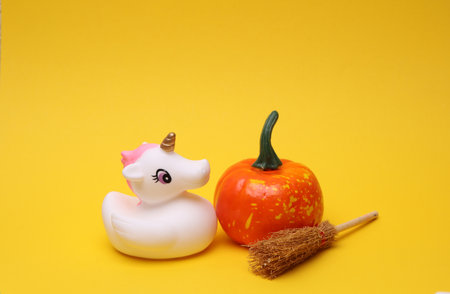 Rubber bath unicorn with halloween decor on a yellow background. Top view.の写真素材