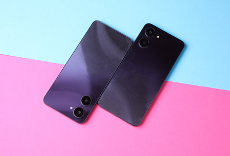 Two modern smartphones with dual camera, view from the back cover. pink blue backgroundの写真素材