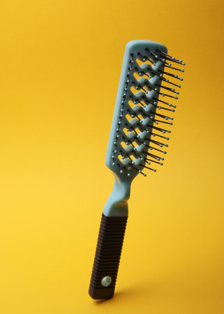 Hair brush, plastic comb on yellow backgroundの写真素材