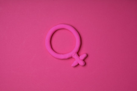 Female gender symbol made of plasticine on pink backgroundの写真素材