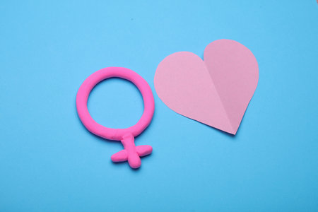 Female gender symbol made of plasticine and heart on blue backgroundの写真素材