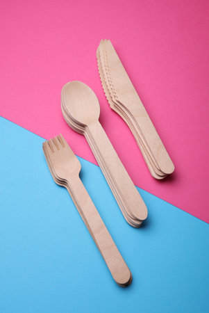 Set of eco wooden knives, forks and spoons on pink blue backgroundの写真素材