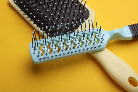 Two Hair brushes, plastic combs on yellow backgroundの写真素材