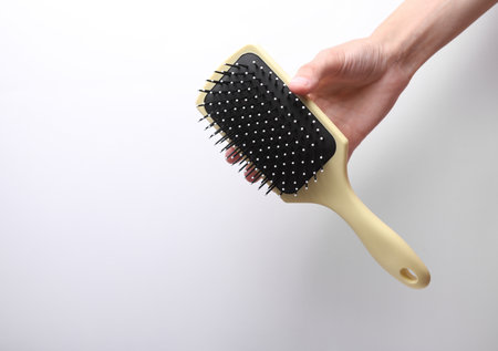 Female hand holding hairbrush on gray backgroundの写真素材