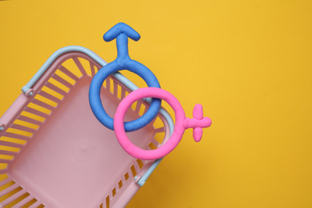 Supermarket basket with female and male gender symbols on yellow backgroundの写真素材