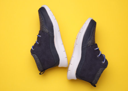 Children's warm sneakers half-boots on a yellow backgroundの写真素材