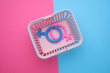 Supermarket basket with female and male gender symbols on blue pink backgroundの写真素材