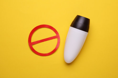 White antiperspirant tube stick with red prohibition sign on yellow backgroundの写真素材