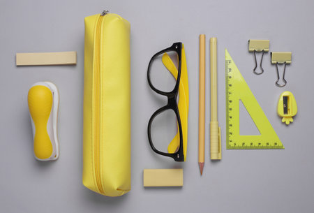 Yellow pencil case with stationery on gray background. Flat layの写真素材