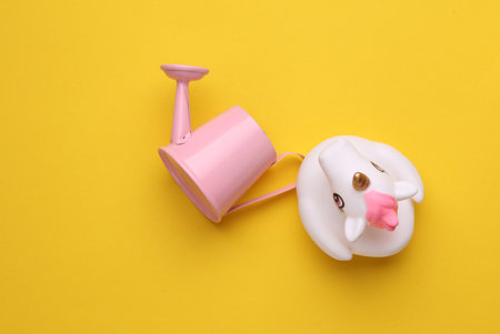 Rubber unicorn with watering can on yellow backgroundの写真素材
